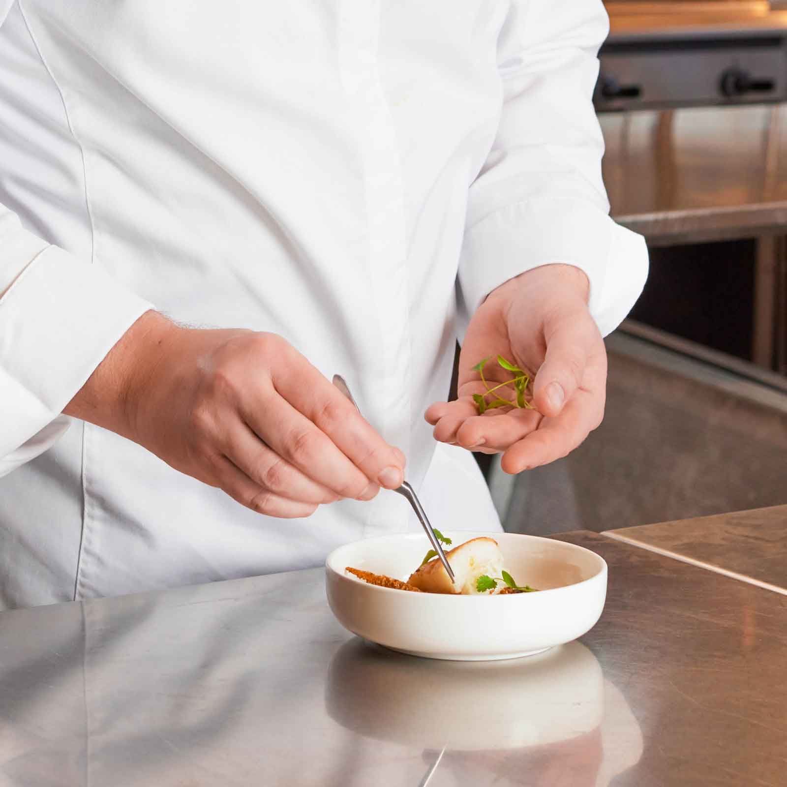 SkyChefs chef plating a dish of gourmet aviation cuisine